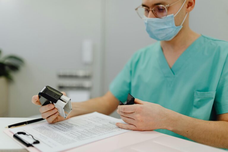 Healthcare worker in scrubs reviewing patient files with a stamp and clipboard.